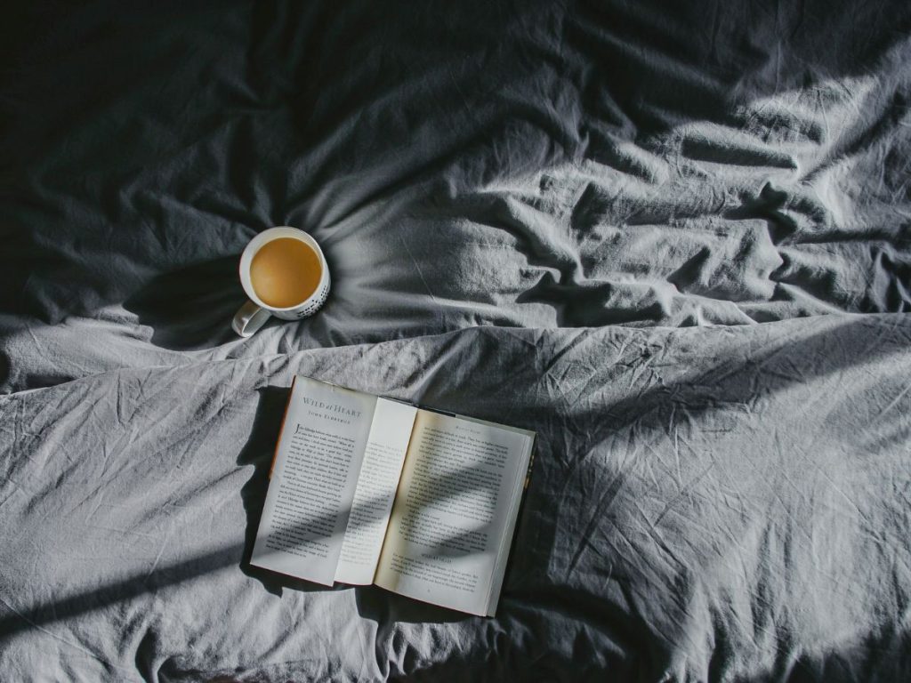 book and coffee cup on bed